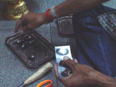 Devotee assists in Covering Bia Gae Amulets